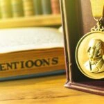 Zlatá medaila s vyrytým portrétom Alfreda Nobela na starom drevenom stole