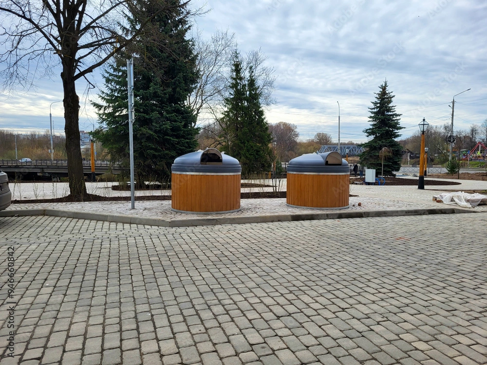 Dva odpadkové koše v parku s dlaždeným chodníkom
